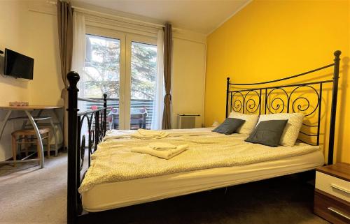a bedroom with a large bed with yellow walls at Évi Apartman in Eger
