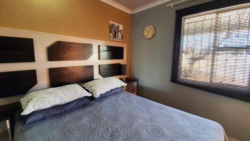 a bedroom with a bed and a clock on the wall at Genesis Self Catering Apartments in Bloemfontein
