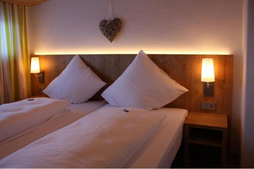 two beds in a hotel room with white pillows at Haus Bergland in Pfronten