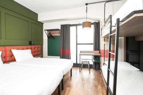 two beds in a room with green walls and a table at Generator Madrid in Madrid
