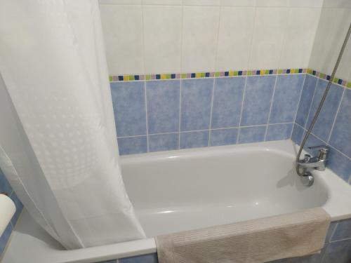 ein Badezimmer mit einer weißen Badewanne mit blauen Fliesen in der Unterkunft Les Jardins de l’Empereur, Hendaye in Hendaye
