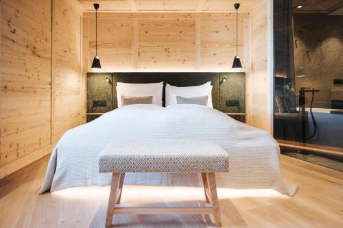 1 dormitorio con 1 cama blanca grande con taburete en Superior Hotel Schneider Ski-in & Ski-out, en Obertauern