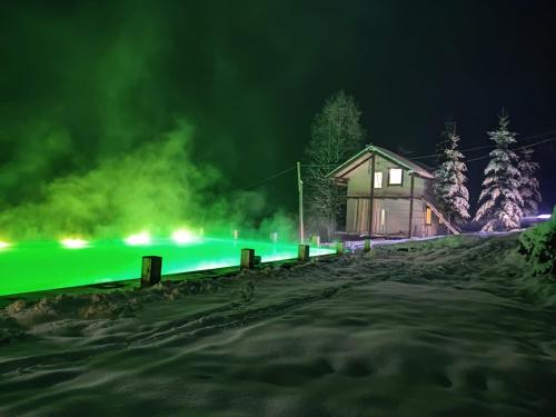 a house with green lights in the snow at night at Khatky Na Penkakh in Vorokhta