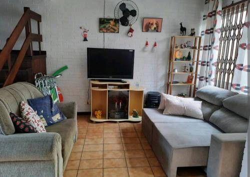 a living room with a couch and a flat screen tv at Sobrado de Caiobá in Matinhos