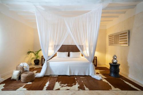 a bedroom with a white bed with a canopy at Lion in the Sun Boutique Hotel & Spa in Malindi
