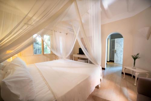 a bedroom with a white bed with a canopy at Lion in the Sun Boutique Hotel & Spa in Malindi