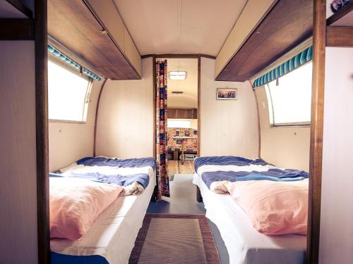 two beds in a room with two windows at Airstream Hotel in Kahla
