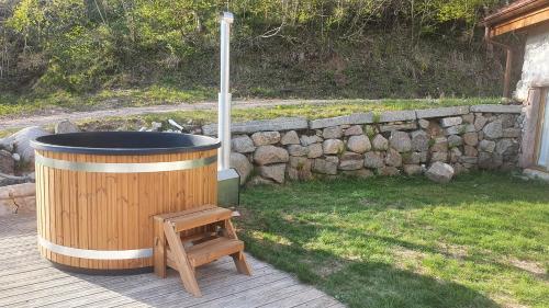 un jacuzzi posé sur une terrasse à côté d'un mur de pierre dans l'établissement LA FERME LES DIGITALES bain nordique, billard, à La Bresse