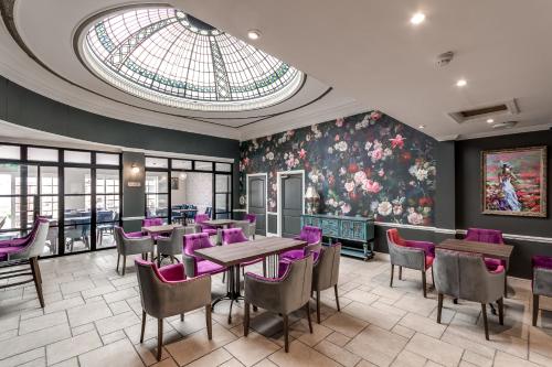 a restaurant with purple chairs and tables and a glass ceiling at The Northwick Arms Hotel in Evesham