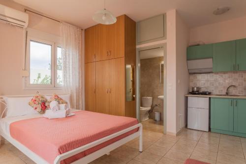 a bedroom with a pink bed and a kitchen at Faidra 03 at TEI in Heraklio