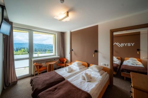 a hotel room with two beds and a large window at Rysy in Bukowina Tatrzańska