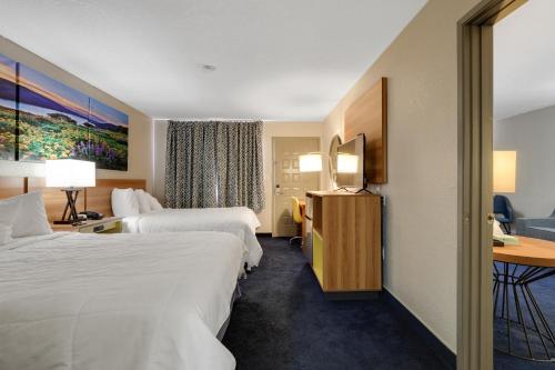 a hotel room with two beds and a desk at Days Inn & Suites by Wyndham Needles in Needles