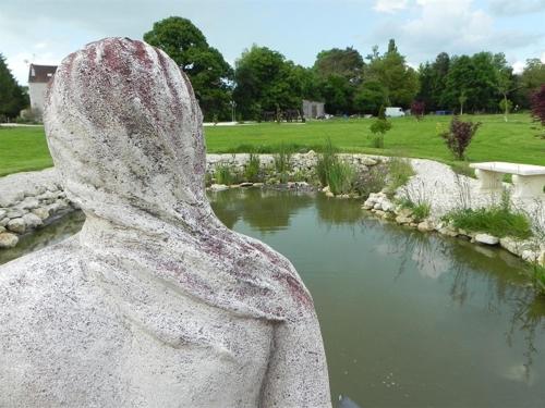 a statue of a butterfly looking at a pond at Le Petit Domaine de Bois Avril in Étais-la-Sauvin