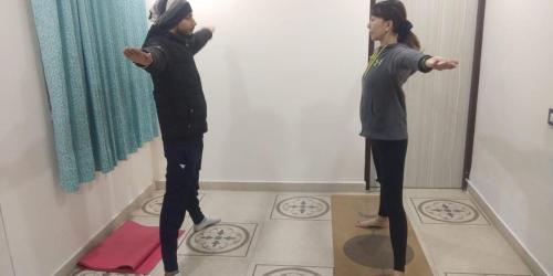 two girls standing in a room looking in a mirror at Krishnabalram wellness & Ayurveda centre in Rishīkesh