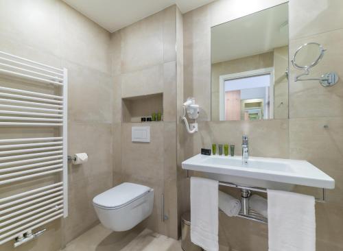 a bathroom with a sink and a toilet and a mirror at Wellness Hotel IRIS in Pavlov