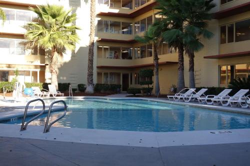 a swimming pool in a hotel with chairs and palm trees at Ramada by Wyndham Sacramento in Sacramento