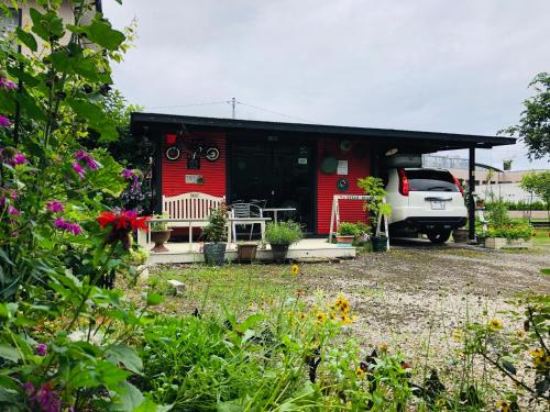 a red house with a car parked in front of it at ガーデンハウス Mako Land in Toyama