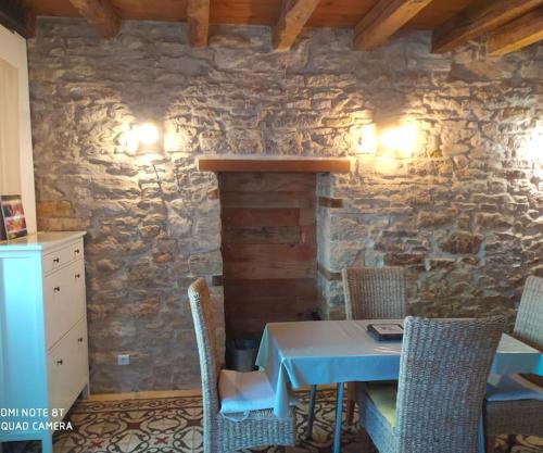 una mesa y sillas en una habitación con una pared de piedra en Élégant T4, en Pesmes