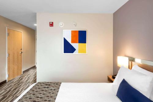 a bedroom with a bed and a painting on the wall at Microtel Inn & Suites by Wyndham Farmington in Canandaigua