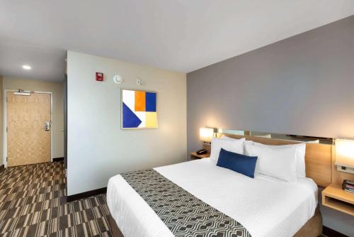 a hotel room with a large bed with blue pillows at Microtel Inn & Suites by Wyndham Farmington in Canandaigua