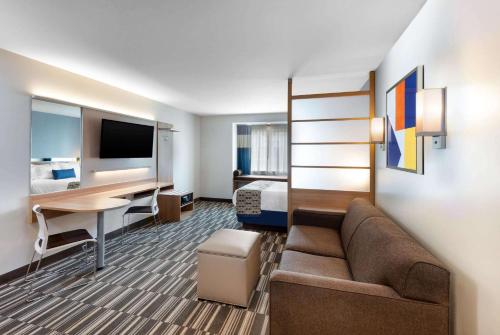 a hotel room with a couch and a desk and a bed at Microtel Inn & Suites by Wyndham Farmington in Canandaigua