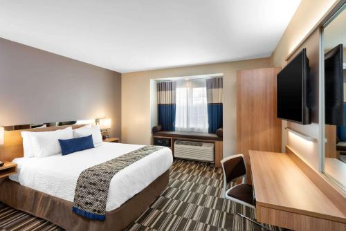 a hotel room with a bed and a flat screen tv at Microtel Inn & Suites by Wyndham Farmington in Canandaigua