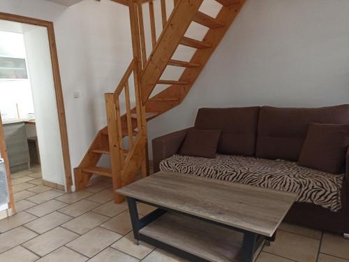 a living room with a couch and a wooden staircase at Le Clos Robinson in Martin-Église