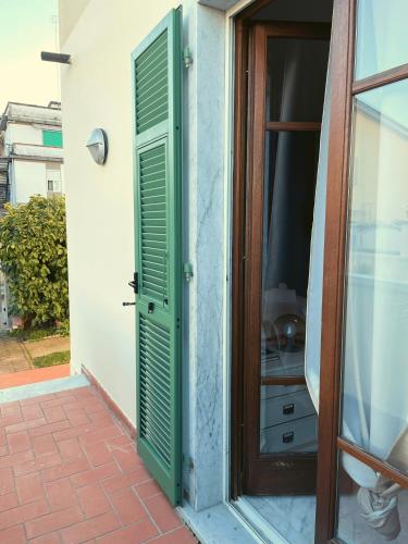 eine Tür mit grünen Rollläden neben einem Fenster in der Unterkunft Confortevole monolocale a 500 mt dal mare in Marina di Carrara