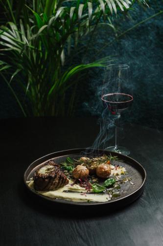 a plate of food on a table with a wine glass at Eglės apartamentai in Palanga