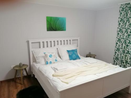 - un lit blanc avec des draps blancs et des oreillers bleus dans l'établissement Rózsa Vendégház Keszthely, à Keszthely