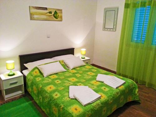 ein Schlafzimmer mit einem grünen Bett und Handtüchern darauf in der Unterkunft Apartments and Rooms King in Mokošica