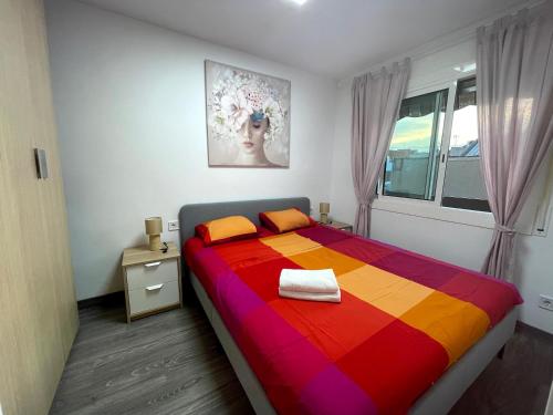 a bedroom with a colorful bed and a window at Sant Adria Beach apartment Wi-Fi Parking Free in Sant Adria de Besos
