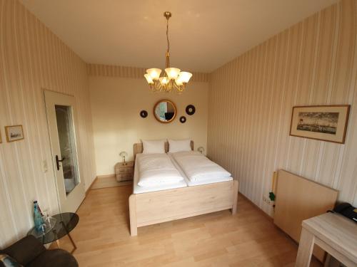 a bedroom with a bed and a chandelier at Hotel Sophien-Café in Leer