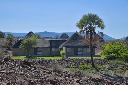 a house with a palm tree in front of it at Palmwag Lodge in Palm