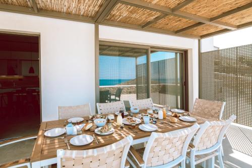 a dining table and chairs on a patio with a view of the ocean at Blue Gres Villa Tinos in Tinos Town