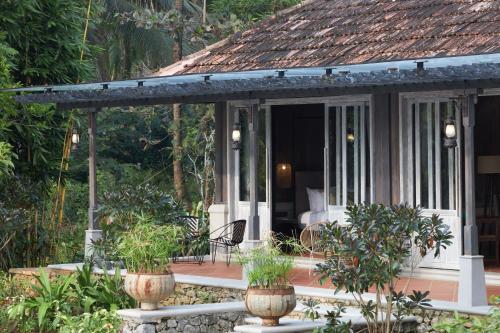 a porch of a house with potted plants on it at Periyar River Lodge in Thattakād