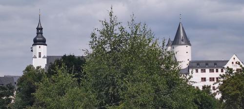 un gran castillo blanco con dos torres detrás de los árboles en Ferienwohnung Dick Schwarzenberg, en Schwarzenberg