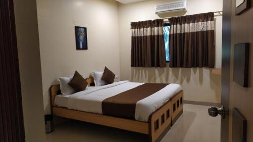 a bedroom with a bed and a window at Aquarius Resort in Pune