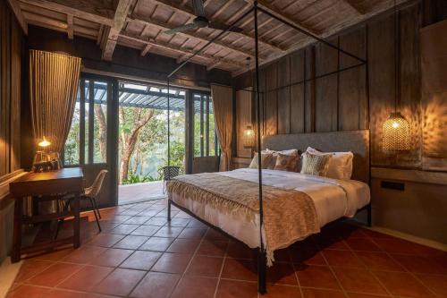 a bedroom with a bed and a desk and a window at Periyar River Lodge in Thattakād