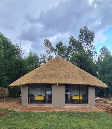a hut with a thatched roof on the grass at FLY FISHING PARADISE ON THE VAAL in Parys