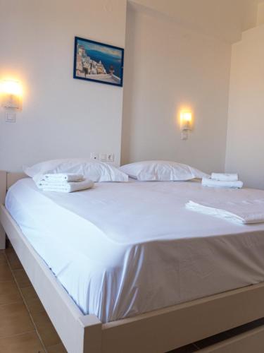 a white bed with white sheets and towels on it at Golden Sun in Ios Chora