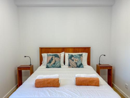 a bedroom with a white bed with two pillows at Baía dos Moinhos in Ribeira Grande