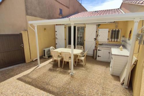 un patio avec une table et des chaises et une cuisine dans l'établissement Joli T2 avec clim, 4/6 personnes,500m de la plage., à Saint-Cyprien
