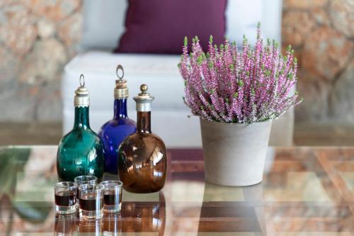 a table with three bottles and a vase with flowers at Amalia Hotel Delphi in Delfoi