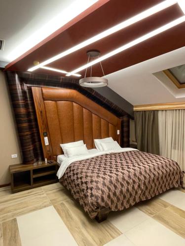 Hotel Havana Loznica في لوزنيكا: غرفة نوم بسرير كبير مع اللوح الخشبي
