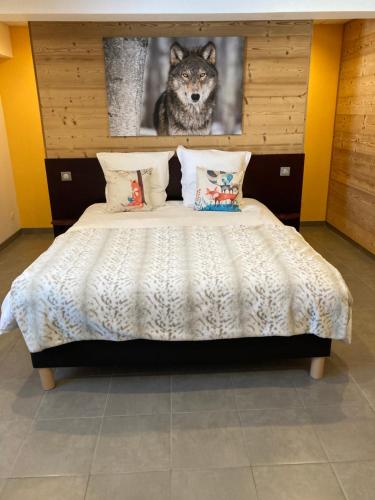 a bedroom with a bed with a wolf picture on the wall at Le Domaine des Fleurs - Appartement La Gentiane in Gérardmer