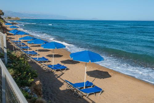 a row of blue chairs and umbrellas on a beach at Hellas Beach Hotel in Skaleta