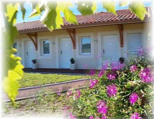 une maison avec des fleurs roses devant elle dans l'établissement Natur'Hôtel, à Ménesplet