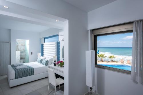 a bedroom with a bed and a desk with a view of the ocean at Hellas Beach Hotel in Skaleta