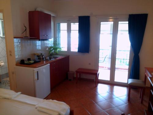 a kitchen with red cabinets and blue curtains at Fantastico Studios #2 in Kalamitsi